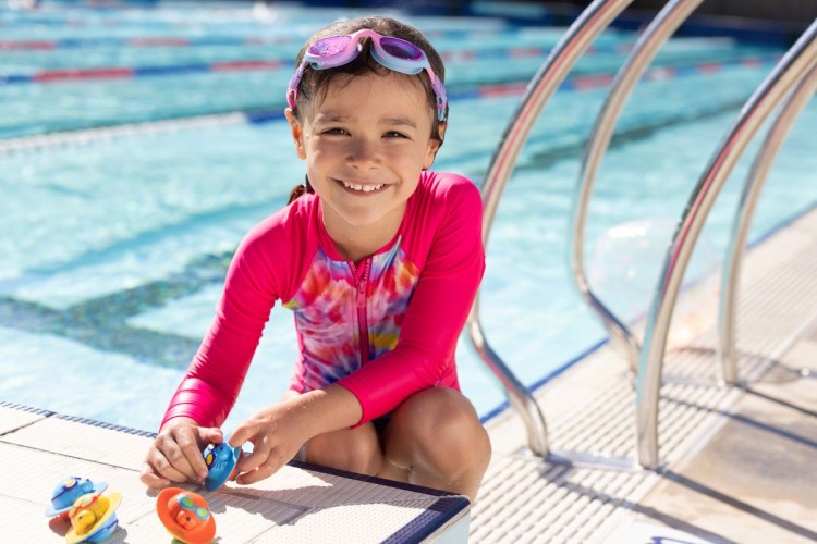 Zoggs-Seal-flips-dziewczynka-siedzi-przy-basenie-z-zabawkami.jpg