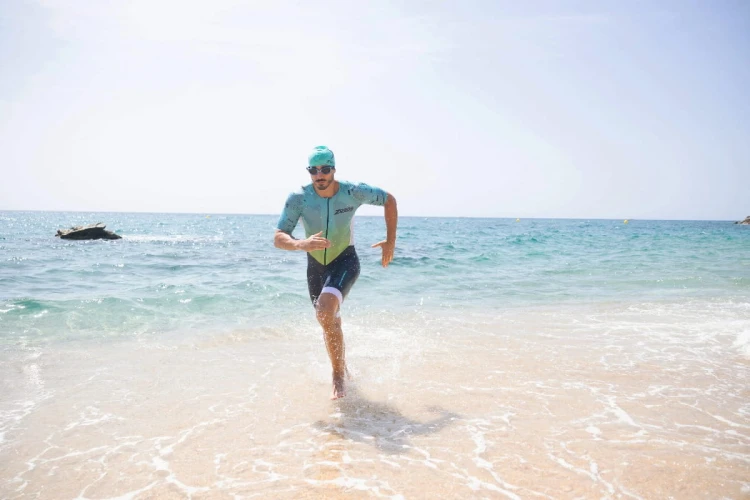 Strój-triathlonowy-turkusowo-biały-mężczyzna-biegnący-po-plaży.jpg