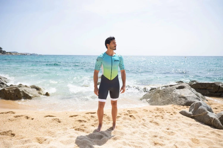 Strój-triathlonowy-turkusowo-biały-mężczyzna-stojący-na-plaży-przodem.jpg